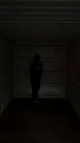 Masked person uses flashlight inside cargo container in North Weald