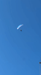 Paraglider soars over Sithonia, Greece in clear afternoon skies