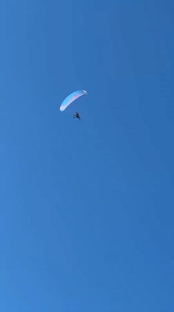 Paraglider soars over Sithonia, Greece in clear afternoon skies