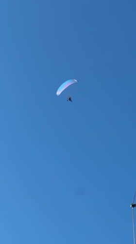 Paraglider soars over Sithonia, Greece in clear afternoon skies