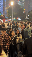 Crowds gather in Shanghai's Pudong district, gazing upward at skyscrapers