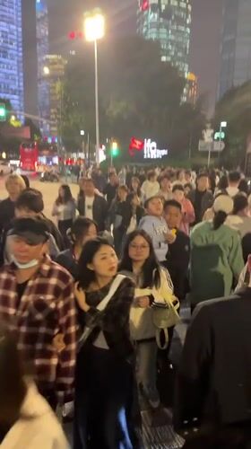 Crowds gather in Shanghai's Pudong district, gazing upward at skyscrapers