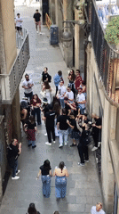 Young crowd with cameras gathers in Barcelona alley