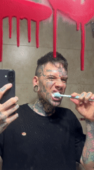 Tattooed person brushes teeth in Buenos Aires bathroom mirror