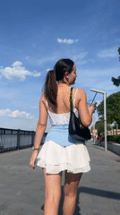 Woman strolls waterfront promenade in Perm on sunny afternoon