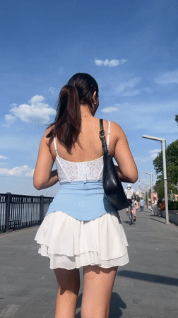 Woman strolls waterfront promenade in Perm on sunny afternoon