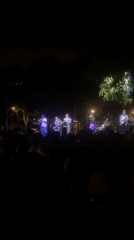 Band performs nighttime outdoor concert with purple stage lighting