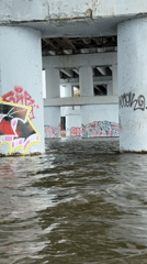 Woman paddleboards under graffitied bridge in Naberezhnye Chelny