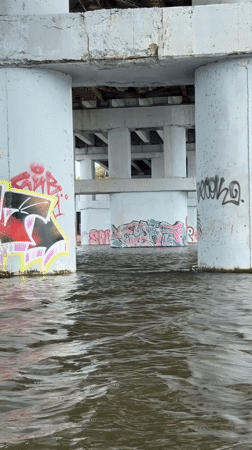 Woman paddleboards under graffitied bridge in Naberezhnye Chelny