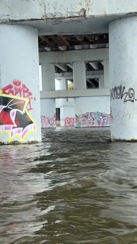 Woman paddleboards under graffitied bridge in Naberezhnye Chelny