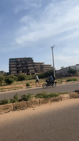 Two pedestrians pass abandoned building in Jos, Nigeria