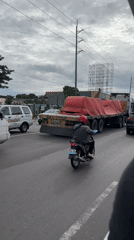 Motorcyclist travels alongside flatbed truck in Davao City traffic