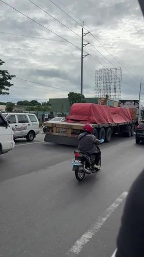 Motorcyclist travels alongside flatbed truck in Davao City traffic
