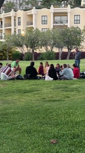 Dozen gather in circle on Funchal lawn near building