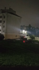 Red vehicle outside lit multi-story building on a quiet night