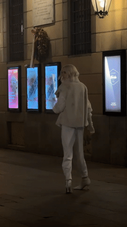 Night scene on a Milan sidewalk, figure in white at center