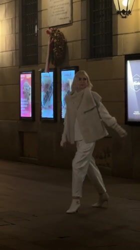 Night scene on a Milan sidewalk, figure in white at center