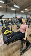 Woman exercises on leg machine at Chaikovsky gym early morning