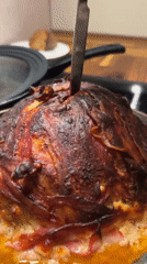 Person cuts bacon-wrapped dome dish in German village