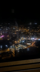 Nighttime La Paz cityscape captured through window with observer's reflection