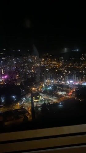 Nighttime La Paz cityscape captured through window with observer's reflection
