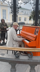 Street musician plays orange piano near Bazhov monument, Yekaterinburg