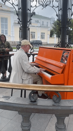 Street musician plays orange piano near Bazhov monument, Yekaterinburg