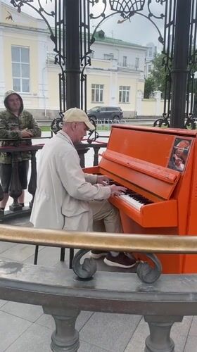 Street musician plays orange piano near Bazhov monument, Yekaterinburg