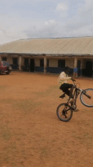 School children play with bicycles on dirt field in Nigeria