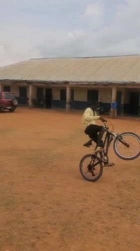 School children play with bicycles on dirt field in Nigeria