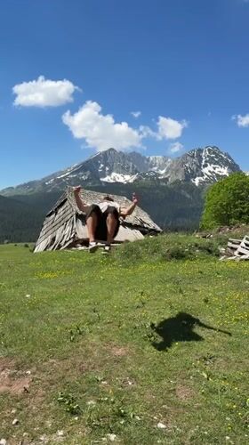 Man dances in rural Montenegro field amid mountain scenery