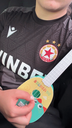 Person plays dinosaur-themed toy ukulele in Sofia
