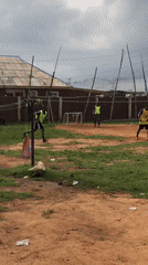 Young men play informal soccer on dirt field