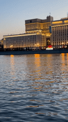 Building illuminated at dusk across Moscow waterway