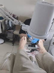 Woman receives pedicure treatment from masked technician