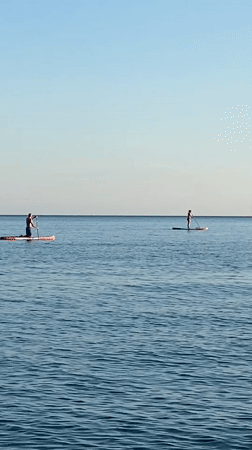 Stand-up paddleboarding on calm Montenegrin waters at sunset