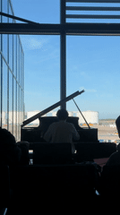 Piano player performs at London airport terminal lounge