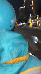 Motorcyclist in turquoise helmet rides through Đà Nẵng streets