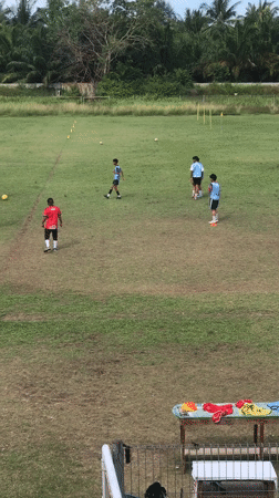 Soccer team practices on Indonesian fields under cloudy skies