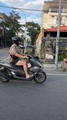 Helmeted scooter rider travels Kuta road in casual attire
