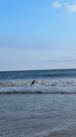 Surfer with red board stands in ocean waters in Mirissa