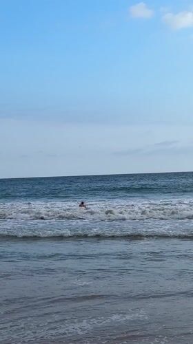 Surfer with red board stands in ocean waters in Mirissa