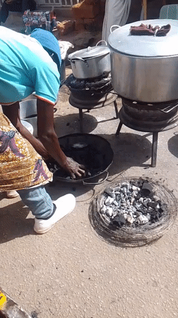 Woman cooks outdoors with charcoal grills in Bukuru Nigeria
