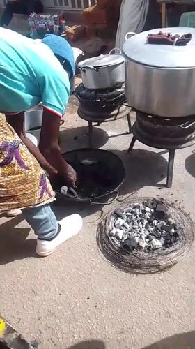 Woman cooks outdoors with charcoal grills in Bukuru Nigeria