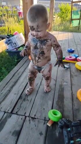 Muddy toddler moment on a backyard wooden deck