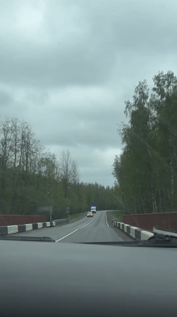 Vehicle crosses rural bridge as ambulance approaches in Russia