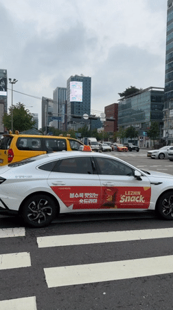Street-level Seoul: taxis, deliveries, billboards, and a vintage car display