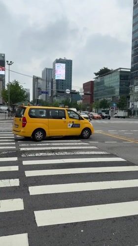 Street-level Seoul: taxis, deliveries, billboards, and a vintage car display