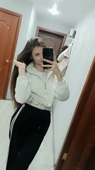 Young woman takes mirror selfies in residential hallway