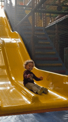Child plays on colorful slides at indoor playground